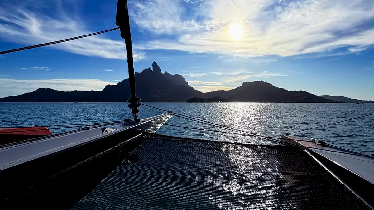 Catamaran net with sunset and silhouette of Mount Otemanu in the distance